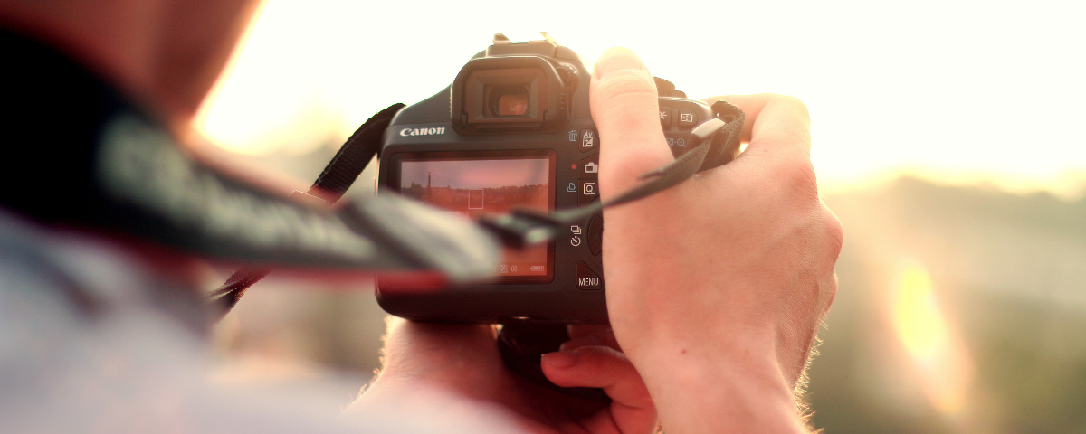 hands holding camera outdoors on sunny day