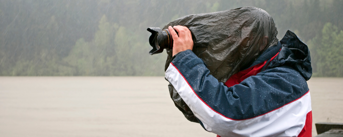 photographer wearing coat and hood and using camera in the rain outdoors